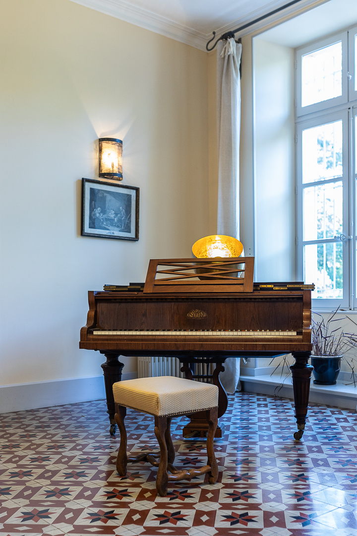 Piano in a castle Antique piano in a room with decorative tiled floor and bright windows.