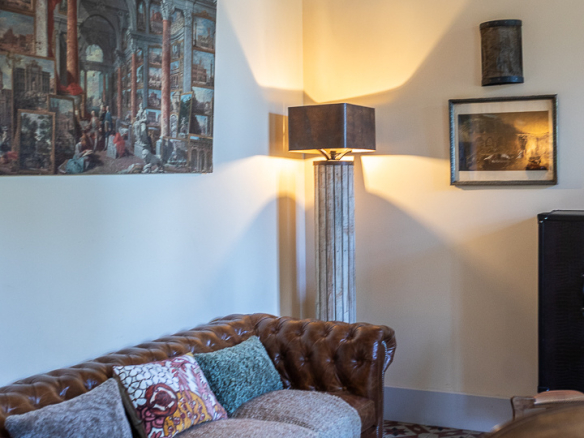 Interior of a living room with a leather sofa, lamp and pictures hanging on the wall.