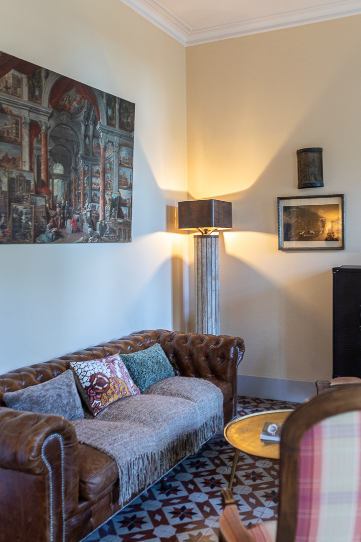 Living room of a castle in Pézenas Interior of a living room with a leather sofa, lamp and pictures hanging on the wall.