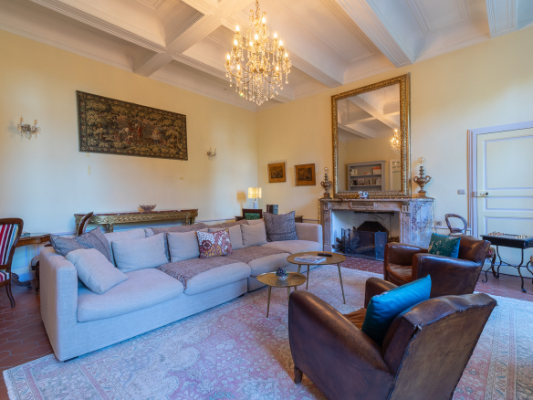 Interior of a spacious living room with a sofa, armchairs and a chandelier at Pézenas Castle.