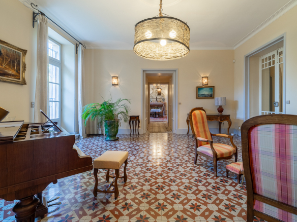 Interior of a castle with a piano, colorful armchairs and a decorative tiled floor.