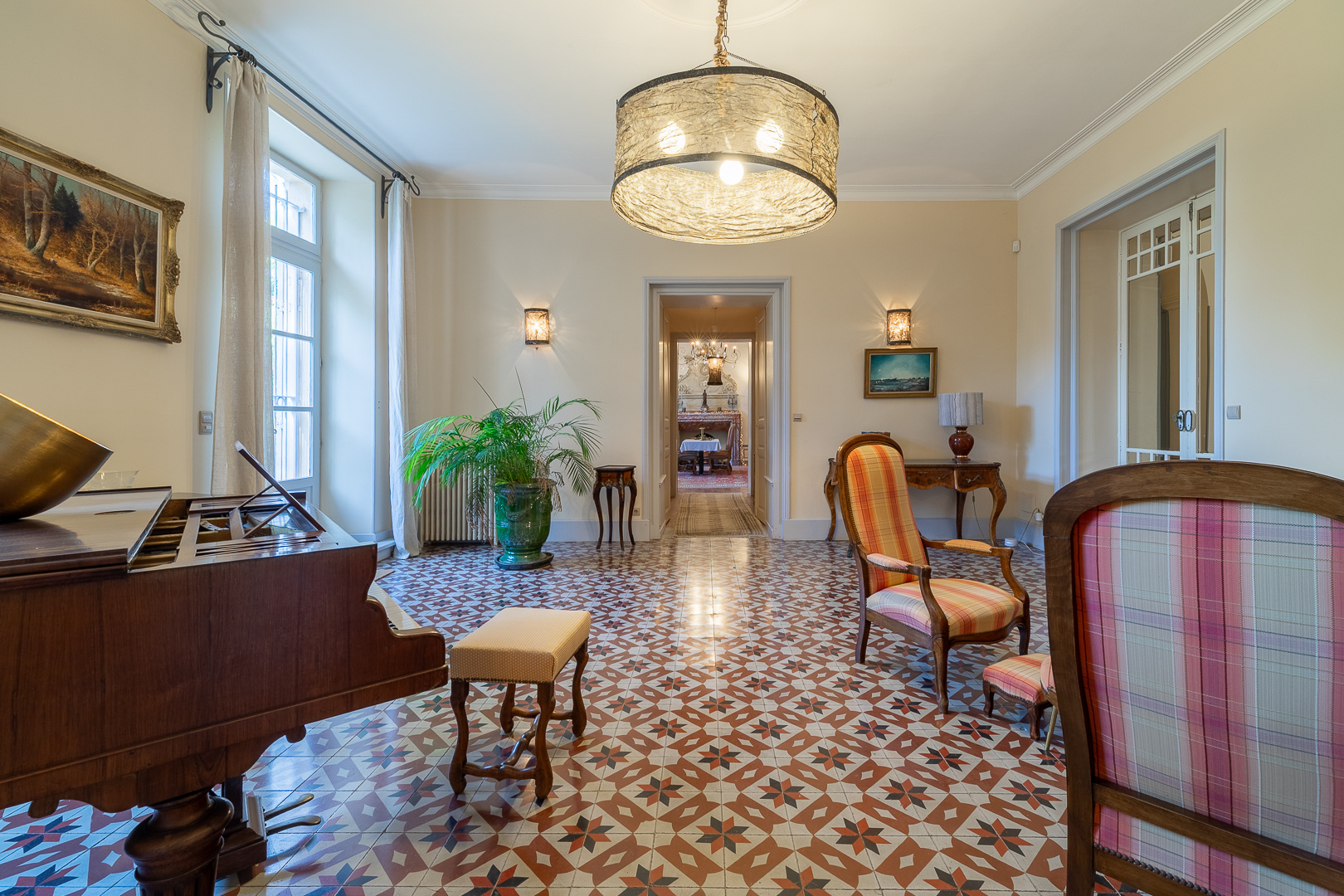 Interior of the exceptional castle in Pézenas Interior of a castle with a piano, colorful armchairs and a decorative tiled floor.