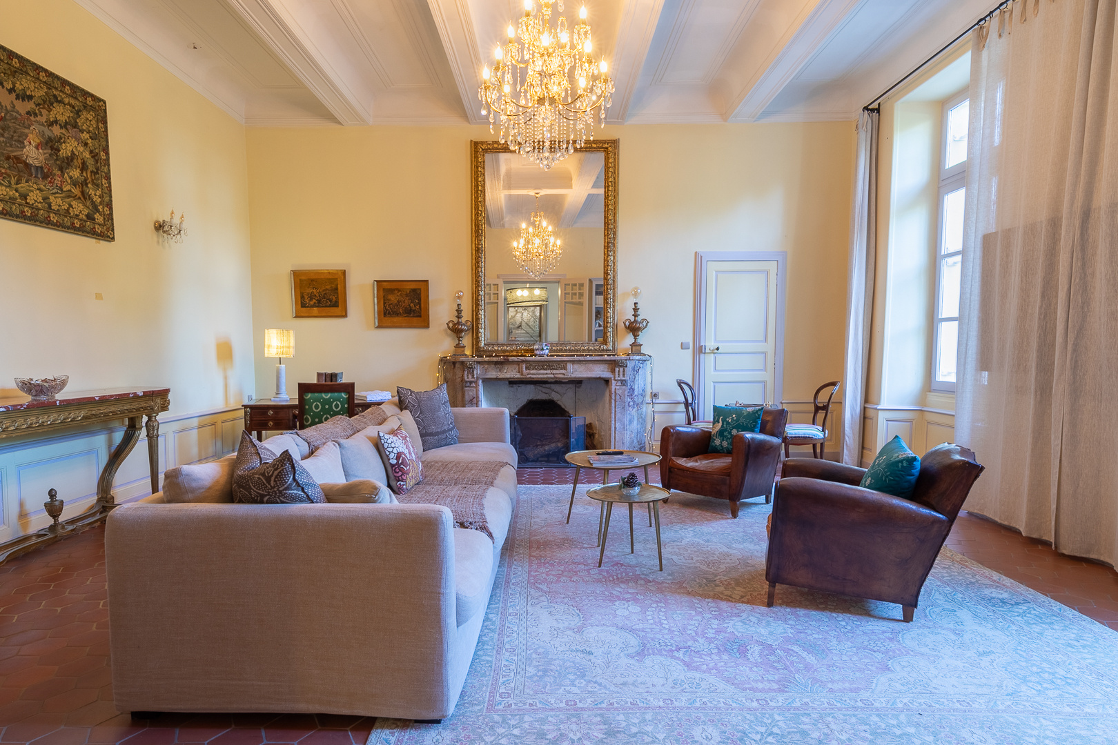 Salon of an exceptional castle in Pézenas Interior of an elegant living room in a castle, with a sofa, armchairs and a large mirror.