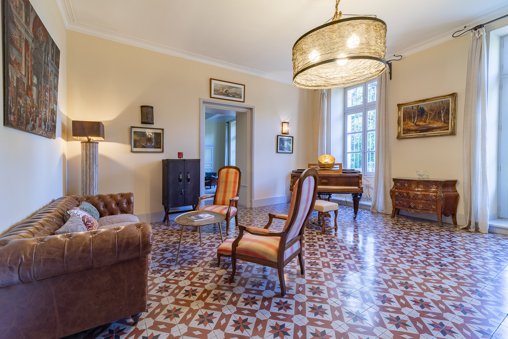 Interior of a castle in Pézenas Interior of a castle with a living room, leather sofa, chairs and piano, elegant decor and tiled floor