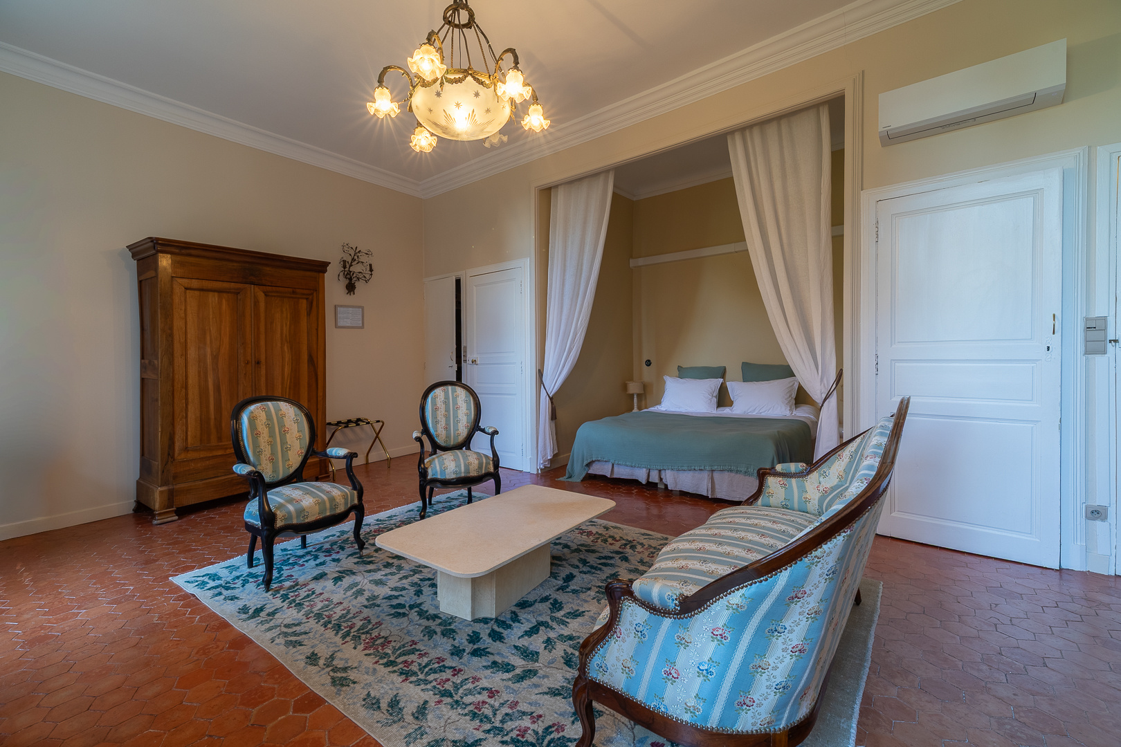 Living room of a castle in Pézenas Interior of an elegant living room in a castle, with armchairs, a coffee table and a bed in the background.