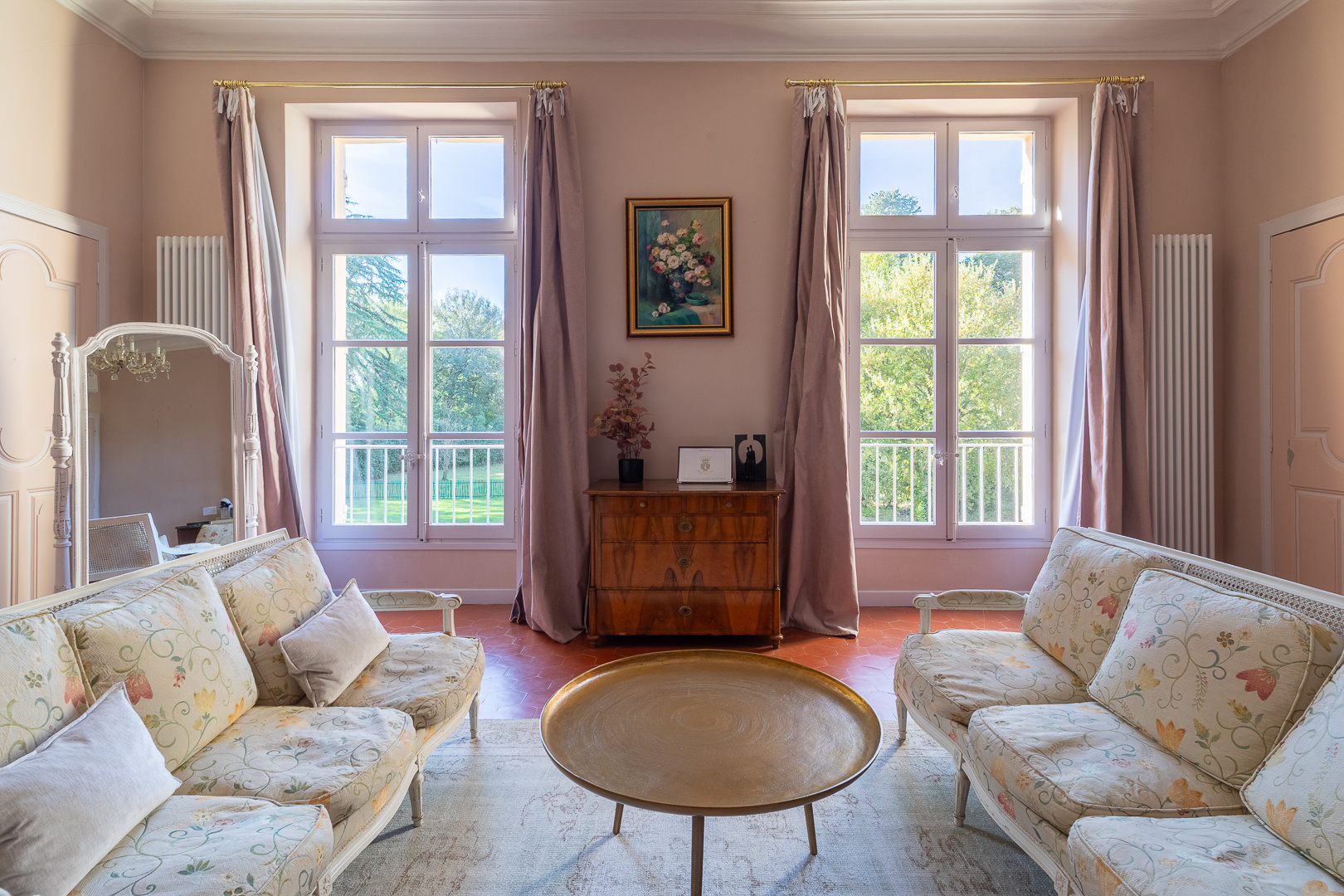 Castle reception room in Pézenas Interior of an elegant living room with two sofas, a coffee table and large windows overlooking a park.