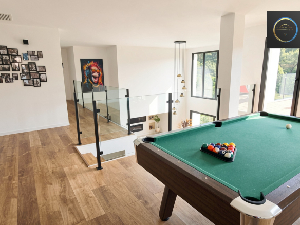 Interior of a contemporary villa with a pool table and large windows.