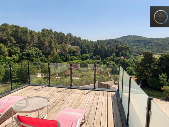 Wooden terrace with deck chairs overlooking a green landscape in Clermont-l'Hérault.