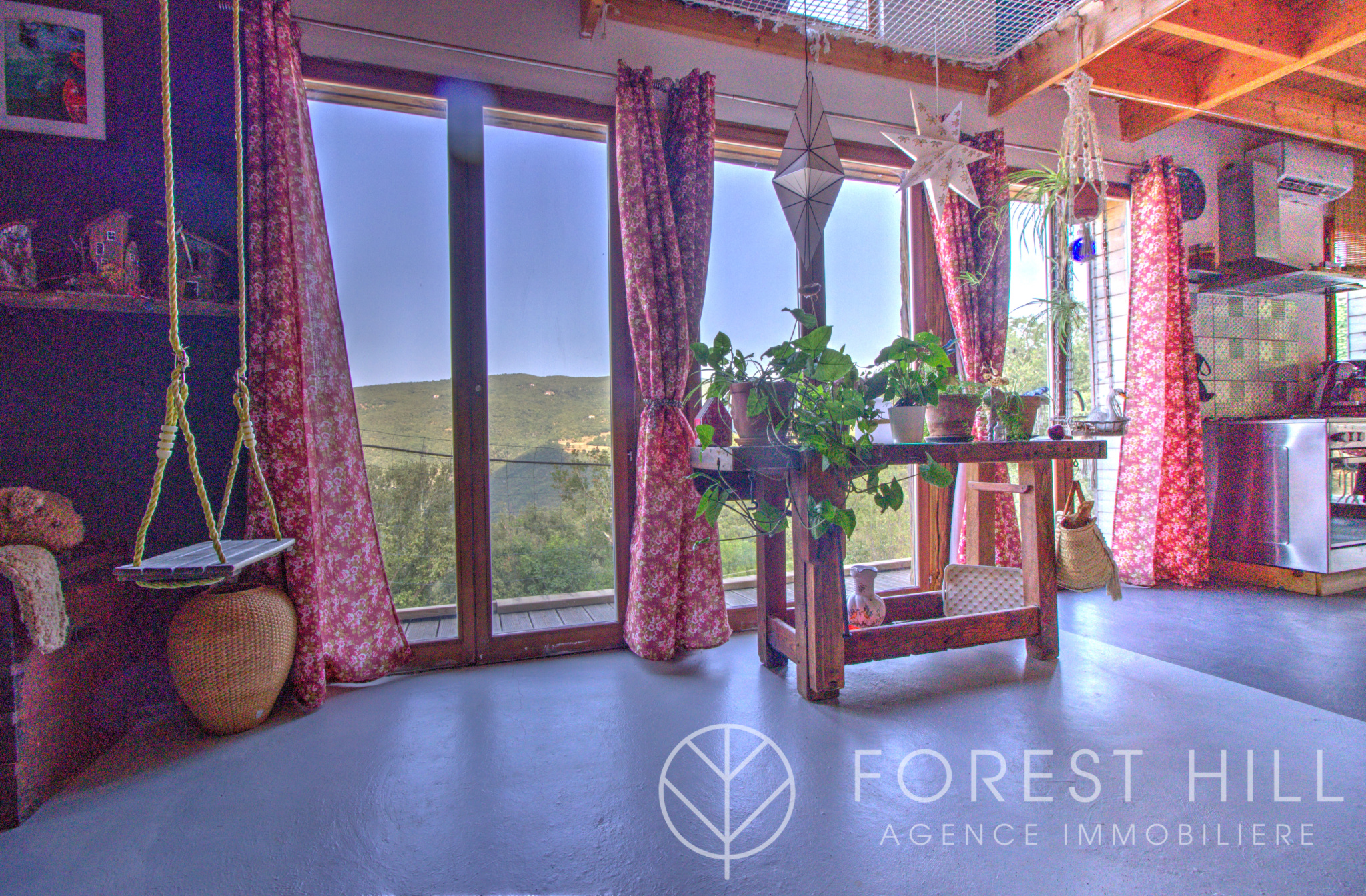 Interior of a house with a view of nature, open windows, plants and warm decoration.