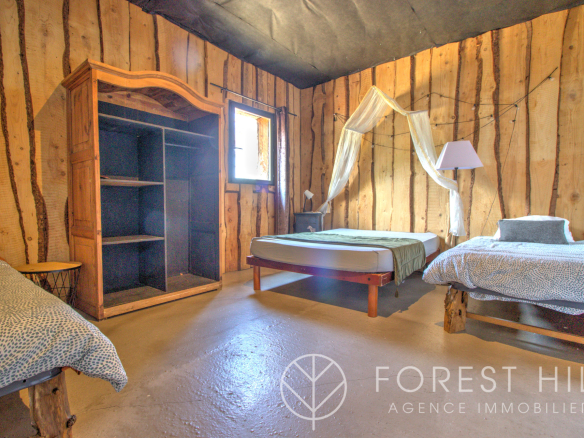 Room in a property with wooden walls, single beds and a wooden wardrobe.