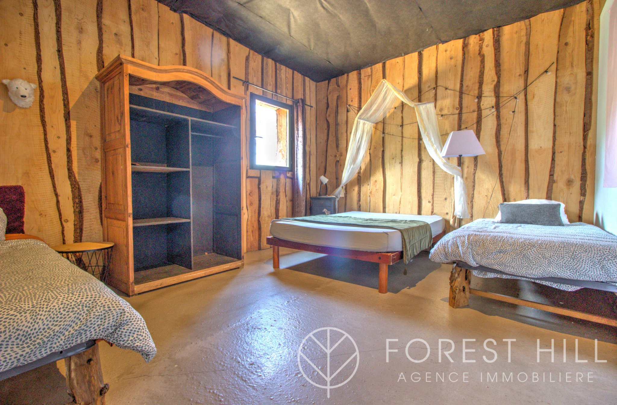 Room in a property with wooden walls, single beds and a wooden wardrobe.