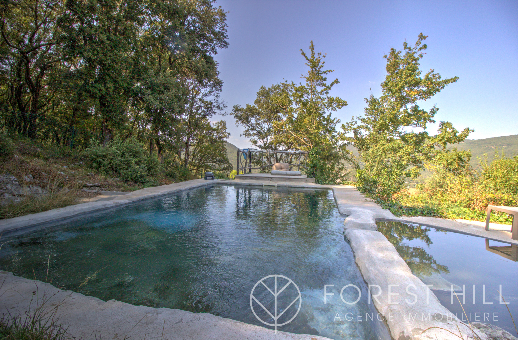 Natural swimming pool surrounded by trees and greenery in a peaceful setting in Montbolo.