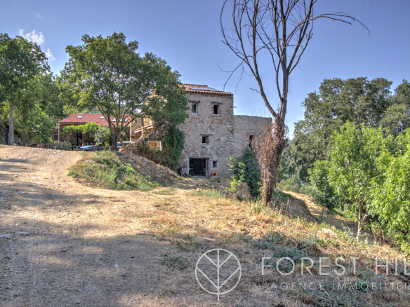 Stone property surrounded by nature in Montbolo, with access road and trees.