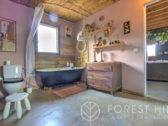 Bathroom with bathtub, wooden furniture and wall decoration in a natural setting.