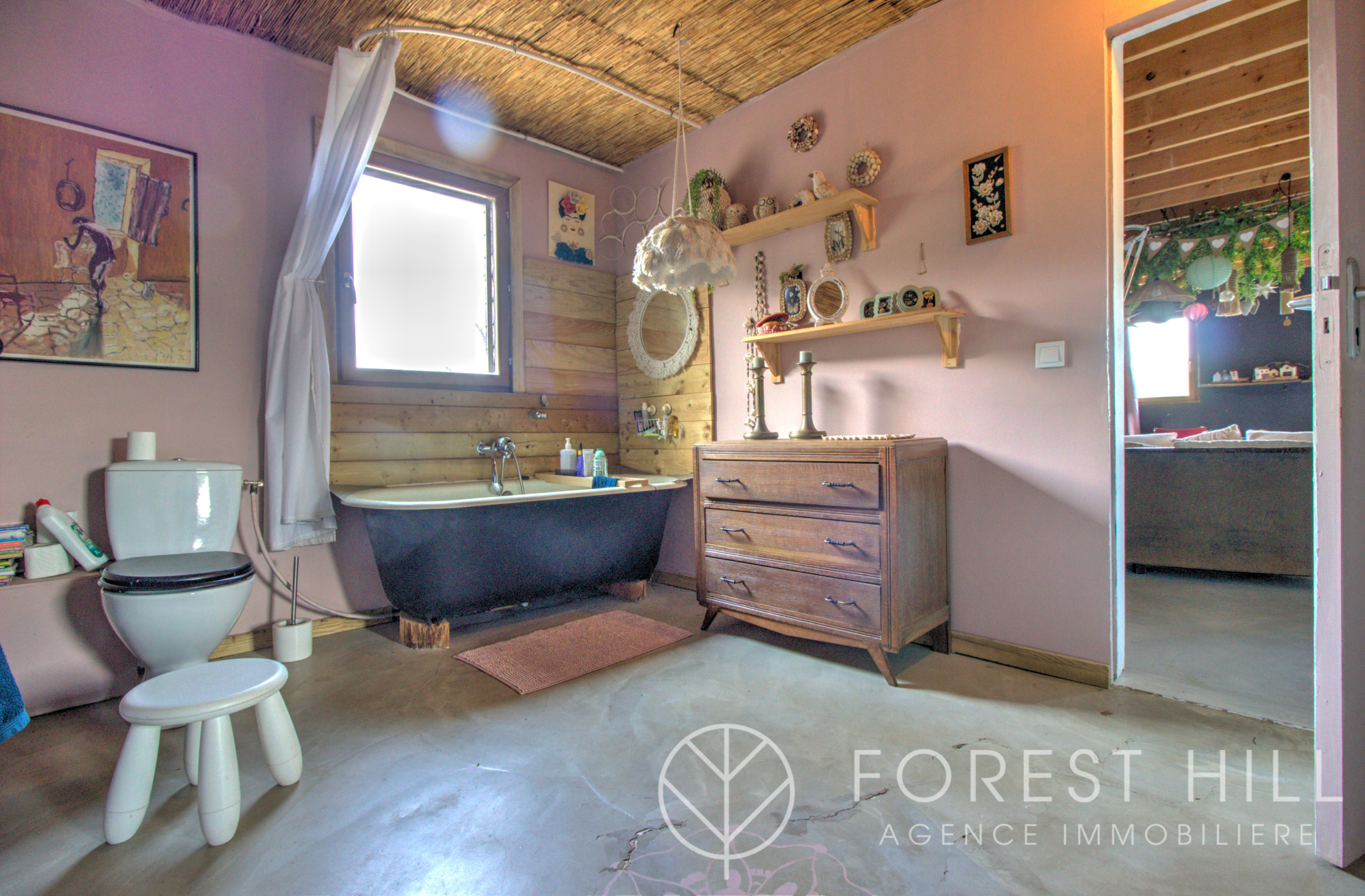 Bathroom with bathtub, wooden furniture and wall decoration in a natural setting.