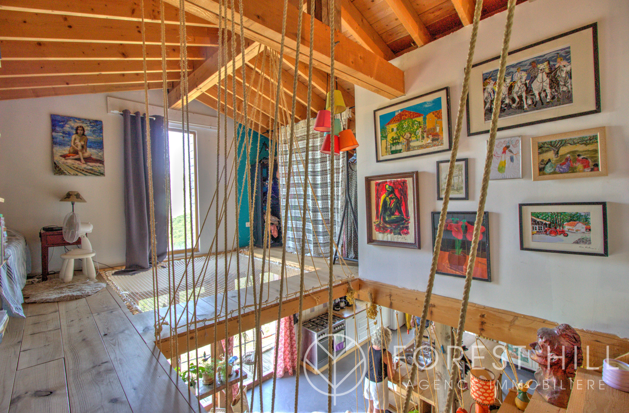 Interior of a property with artwork hanging on the walls and a wooden mezzanine.