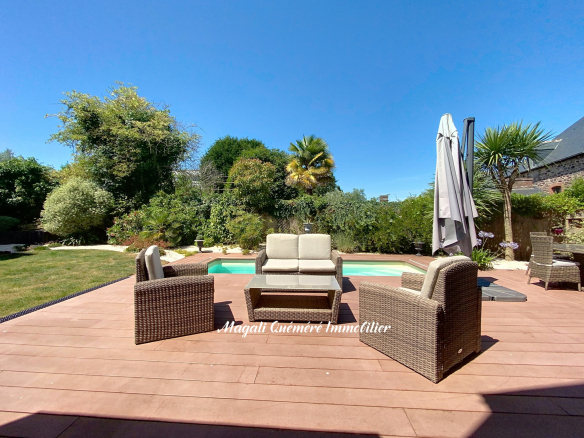 Terrasse en bois avec mobilier de jardin et piscine, entourée de verdure à Montfort-sur-Meu.
