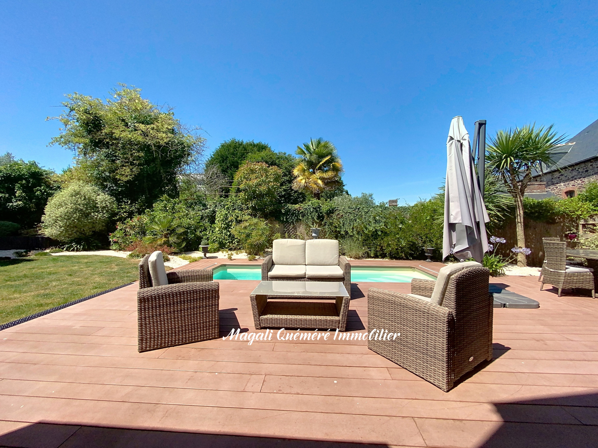 Terrasse en bois avec mobilier de jardin et piscine, entourée de verdure à Montfort-sur-Meu.