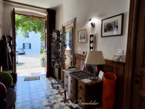 Entrée d'une maison de caractère à Ustaritz avec un sol en carrelage et des murs en bois.