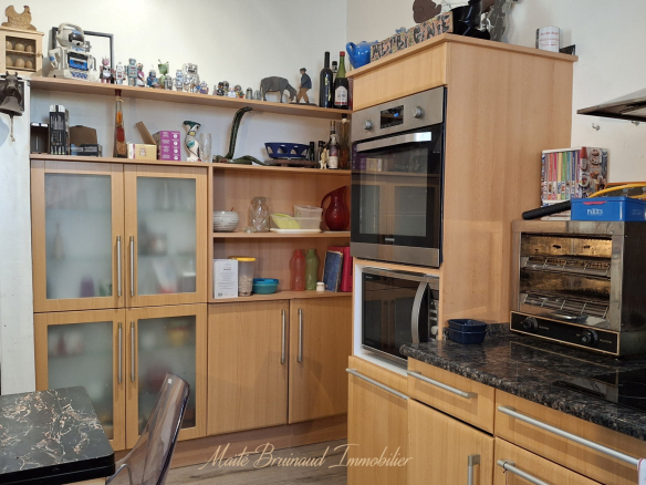 Cuisine moderne avec meubles en bois et appareils électroménagers intégrés.