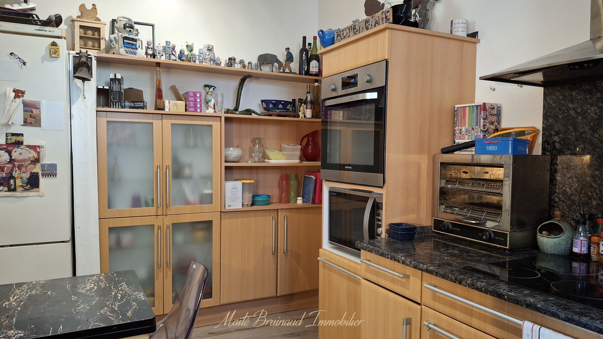 Cuisine moderne avec meubles en bois et appareils électroménagers intégrés.