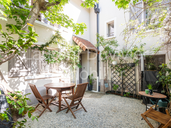 Cour intérieure d'une maison vigneronne rénovée avec des chaises et une table en bois.