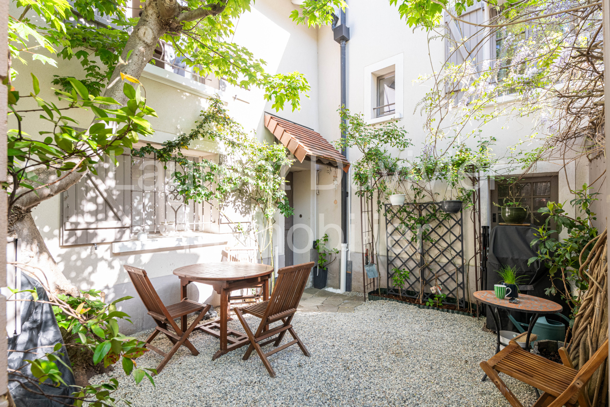 Cour intérieure d’une maison vigneronne Cour intérieure d'une maison vigneronne rénovée avec des chaises et une table en bois.