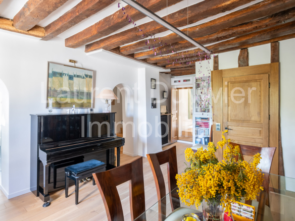 Intérieur d'une maison vigneronne rénovée avec poutres apparentes et piano dans le salon.