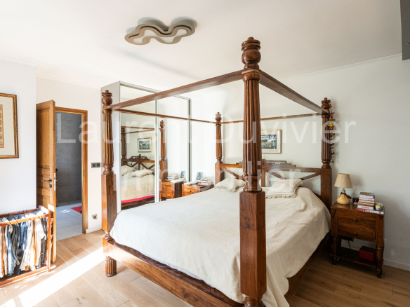 Chambre d'une maison vigneronne rénovée avec un lit à baldaquin et des meubles en bois.