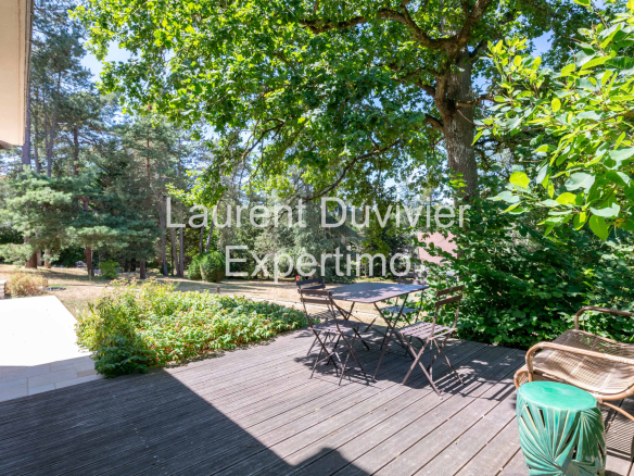 Terrasse en bois avec mobilier de jardin entourée de verdure à Auffargis.