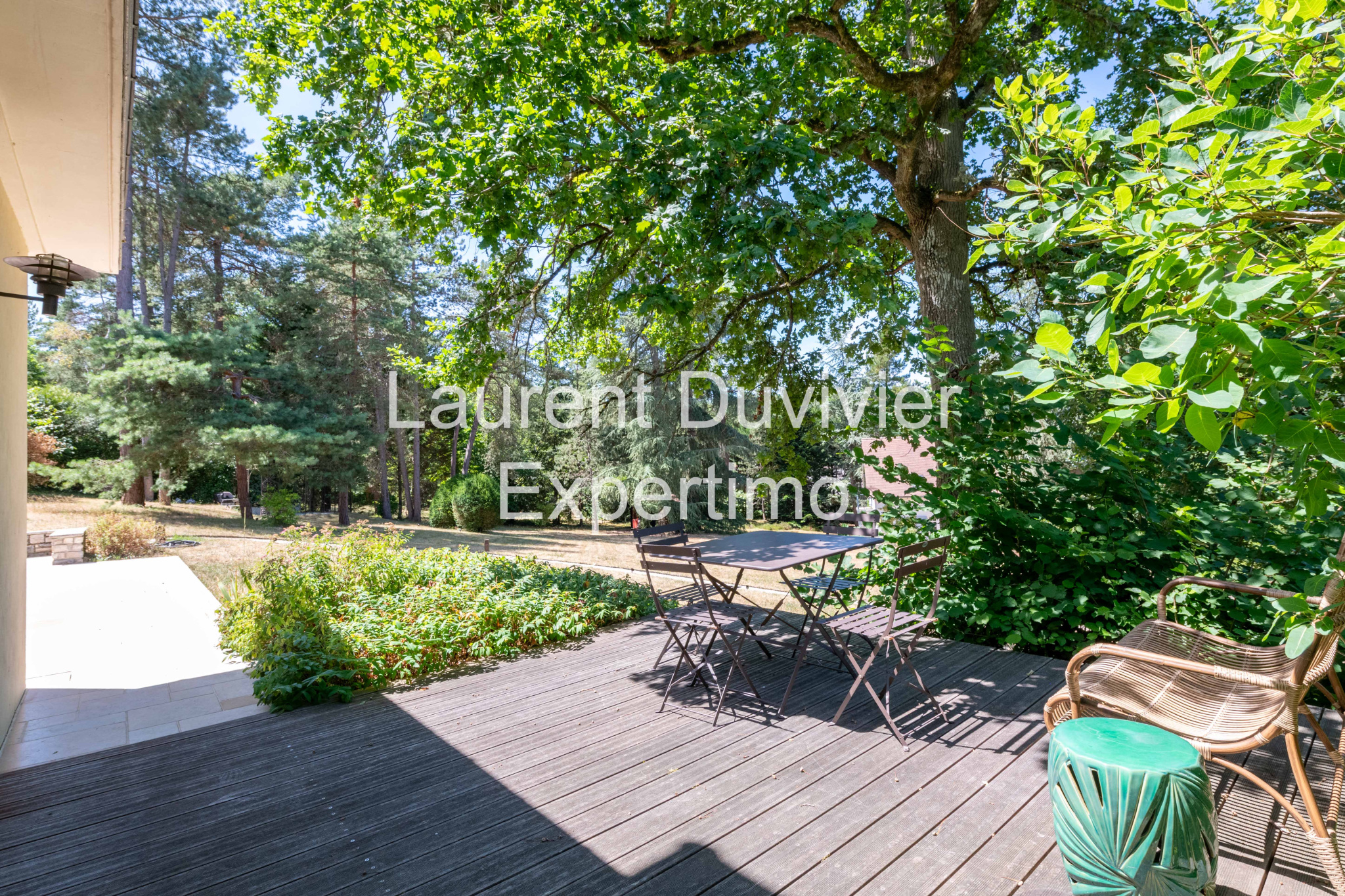 Terrasse en bois avec mobilier de jardin entourée de verdure à Auffargis.