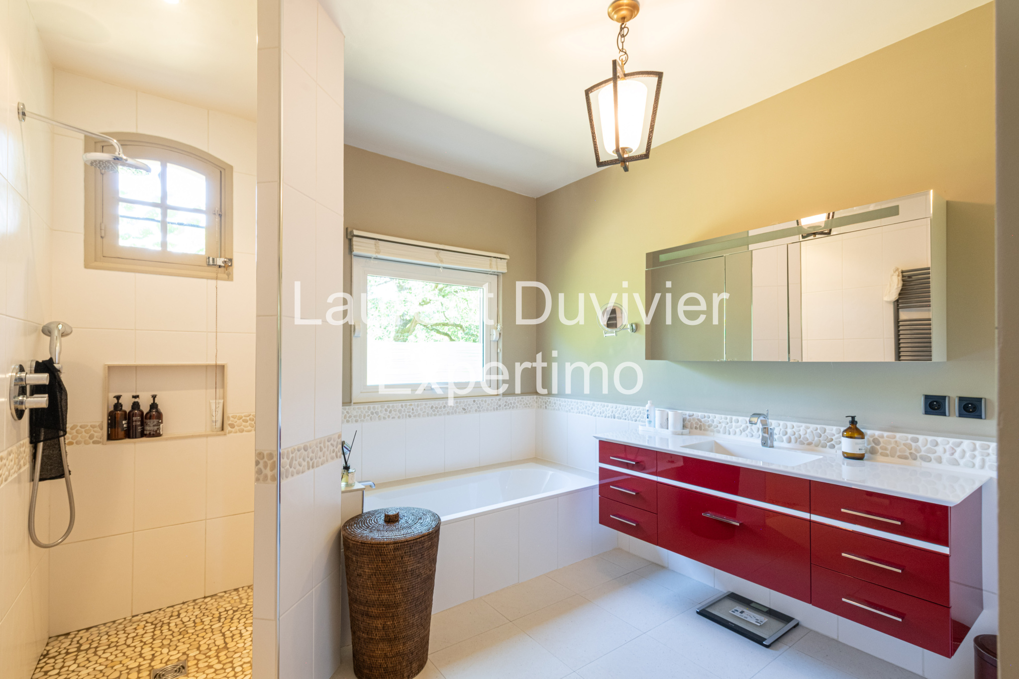 Salle de bain moderne avec douche et baignoire, murs clairs et meuble rouge à Auffargis.