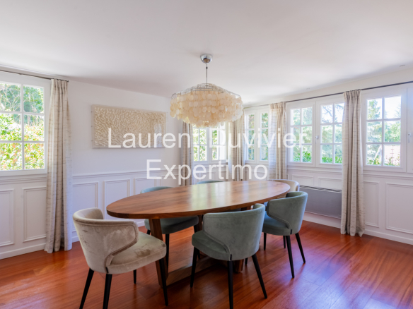 Salle à manger lumineuse avec une grande table ronde et des chaises confortables.