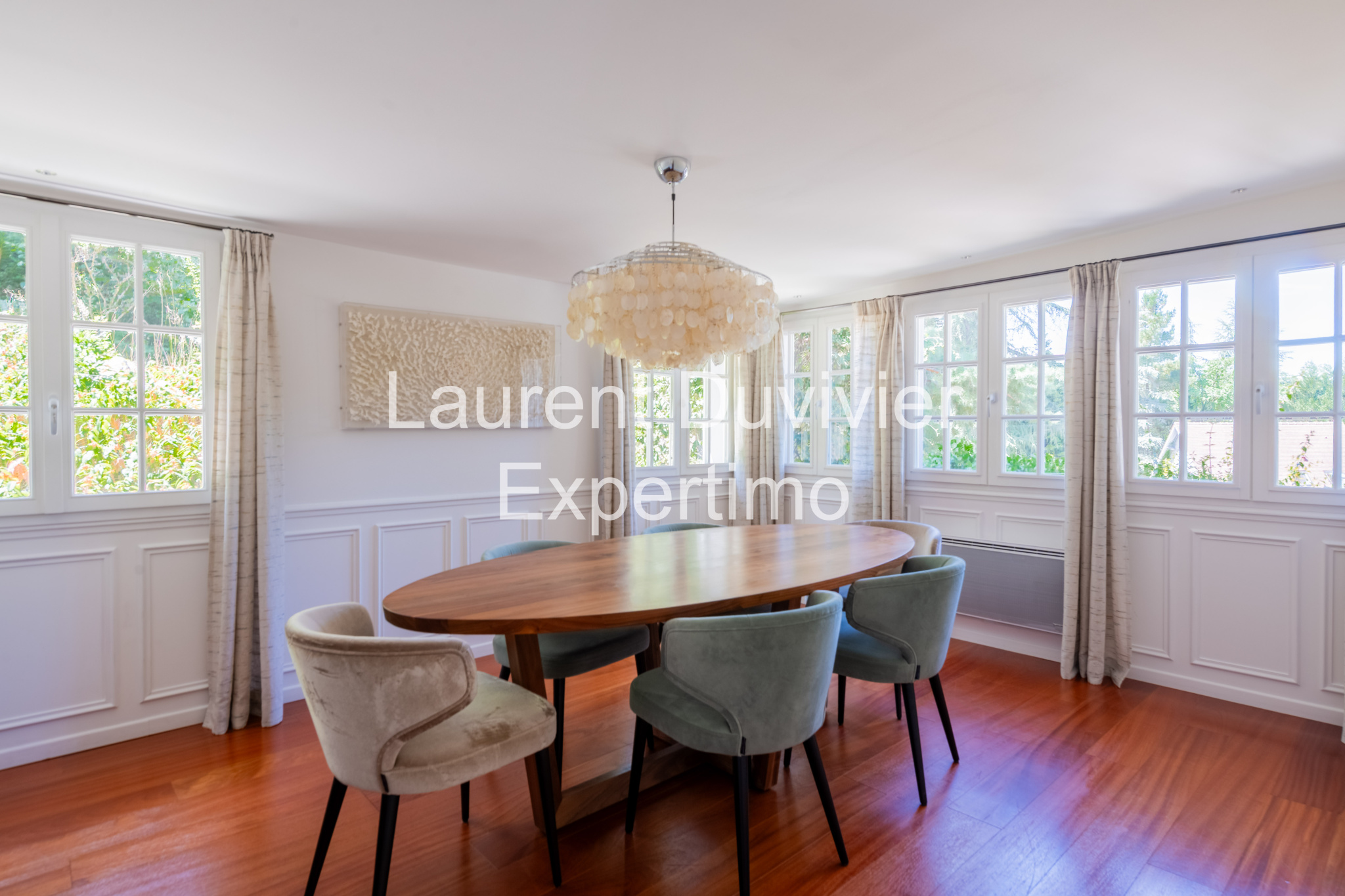 Salle à manger lumineuse avec une grande table ronde et des chaises confortables.