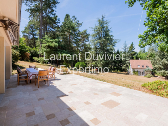 Terrasse d'une propriété à Auffargis, entourée de verdure et d'arbres.