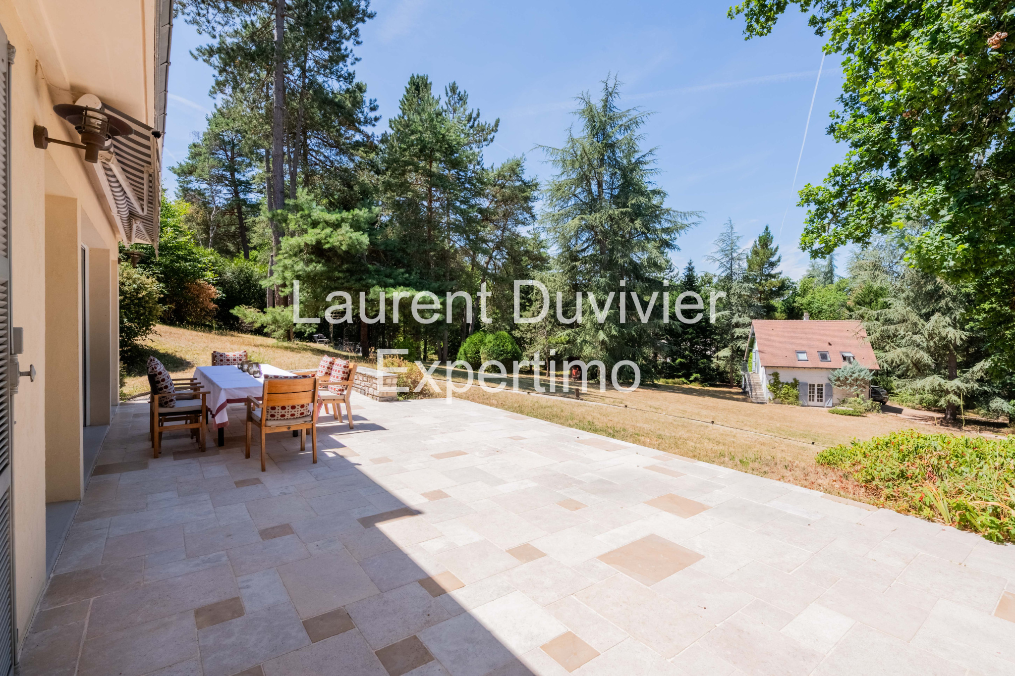Terrasse d'une propriété à Auffargis, entourée de verdure et d'arbres.