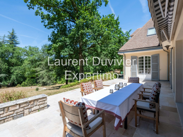 Terrasse d'une propriété à Auffargis avec une table et des chaises, entourée de verdure.