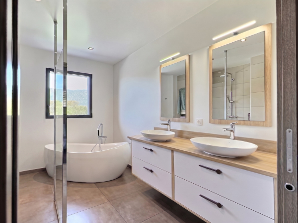 Salle de bain moderne avec baignoire et double vasque dans une maison contemporaine.