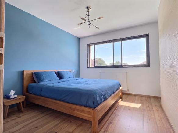 Chambre d'une maison contemporaine à Menthonnex-en-Bornes, avec un lit en bois et un mur bleu.