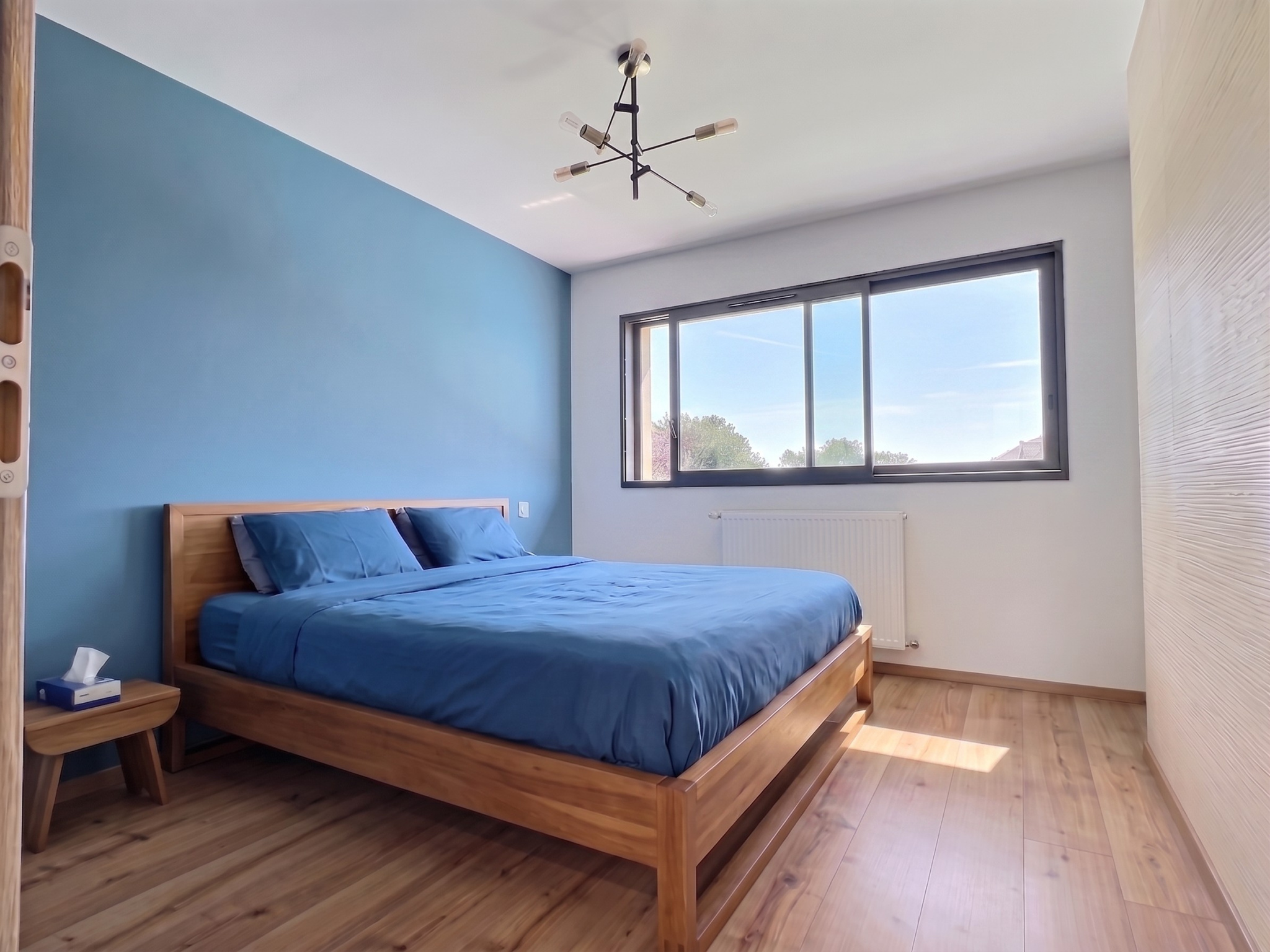 Chambre moderne à Menthonnex-en-Bornes Chambre d'une maison contemporaine à Menthonnex-en-Bornes, avec un lit en bois et un mur bleu.