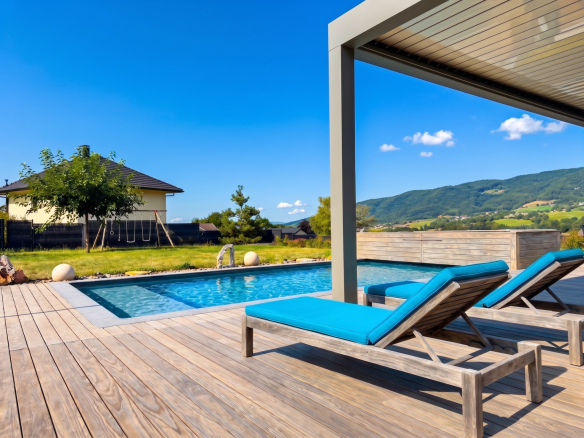 Terrasse avec chaises longues et piscine, vue sur paysage à Menthonnex-en-Bornes.