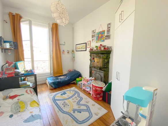 Chambre d'un appartement ancien avec cheminée, lit, tapis et fenêtres à Paris 12ème.