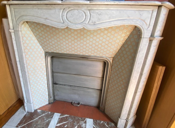 Cheminée en marbre avec décor en faïence dans un appartement ancien à Paris.