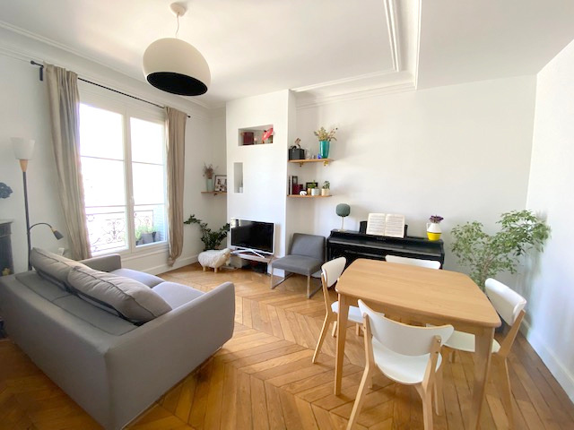 Salon d’un appartement ancien à Paris Salon lumineux d'un appartement ancien à Paris, avec canapé, télévision et piano.
