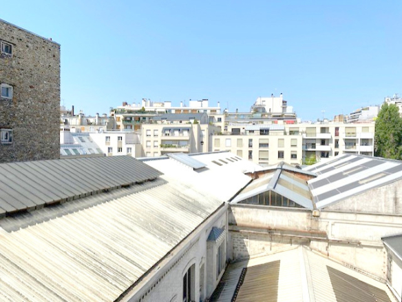 Vue depuis un immeuble ancien à Paris 12ème, montrant des toits et bâtiments environnants.