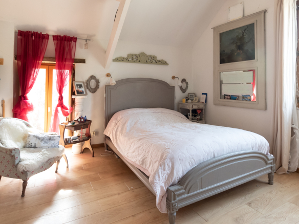 Chambre avec lit double et fauteuil dans une maison de charme à Guyancourt.