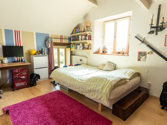 Chambre avec lit double, bureau et décoration colorée dans une maison de charme.