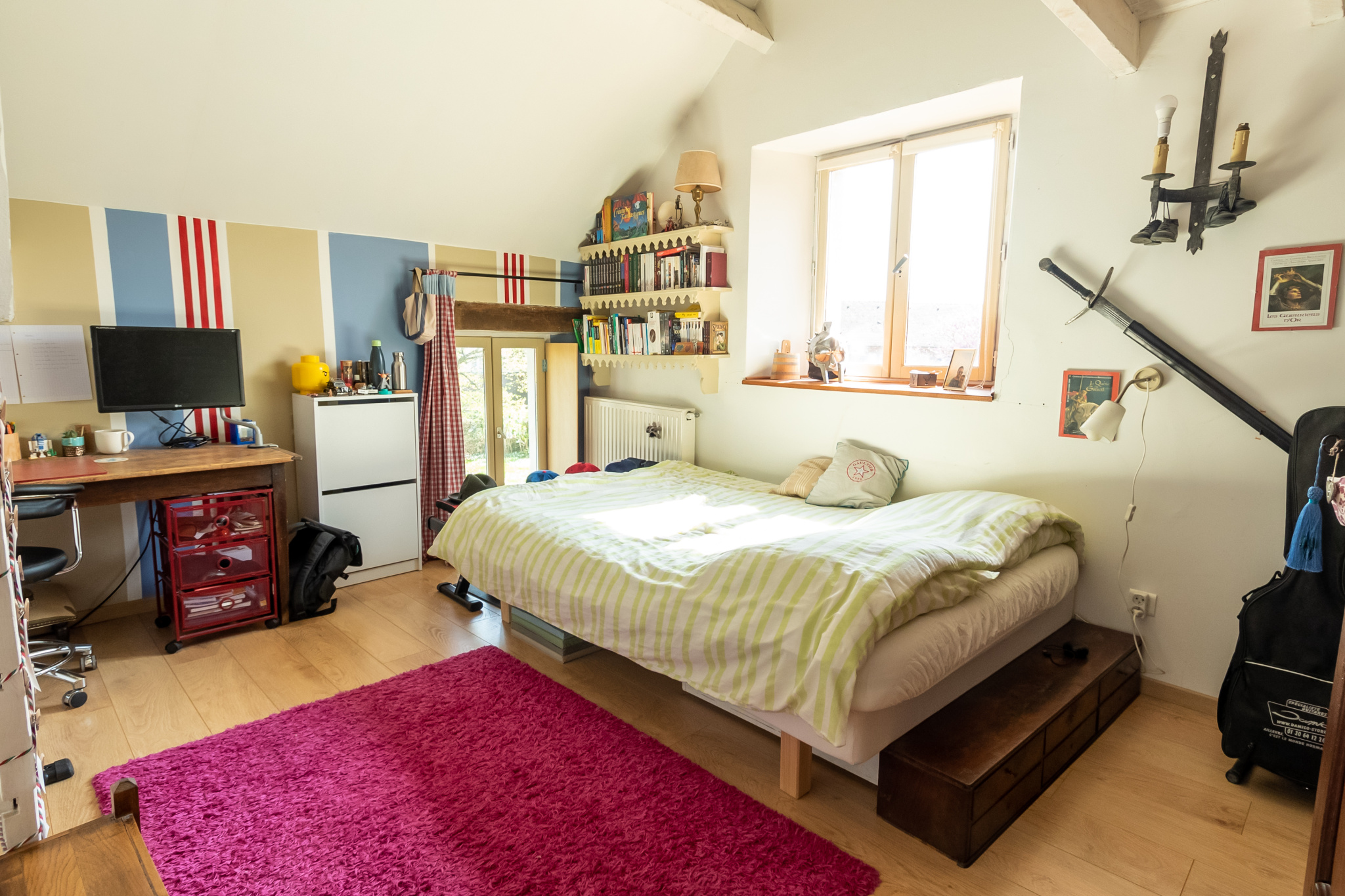 Chambre avec lit double, bureau et décoration colorée dans une maison de charme.