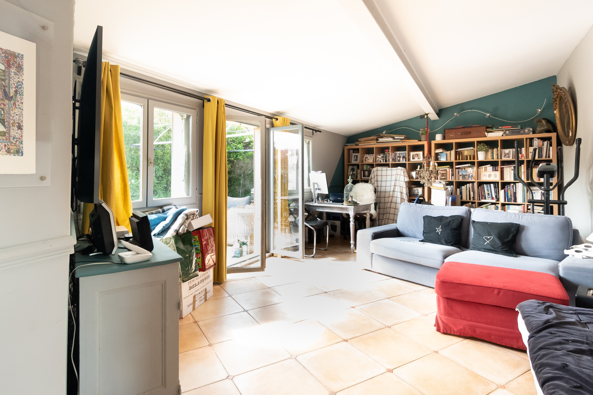 Intérieur d'une maison de charme avec un séjour lumineux et des étagères remplies de livres.