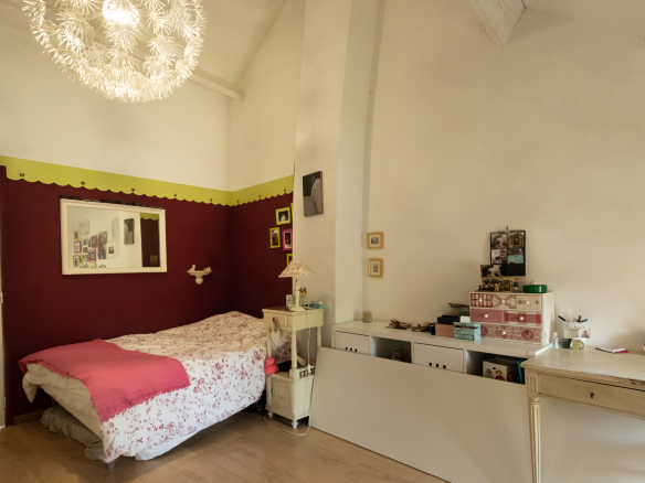 Chambre avec lit, décoration simple et lumineuse, murs rouges et blancs, meubles en bois.